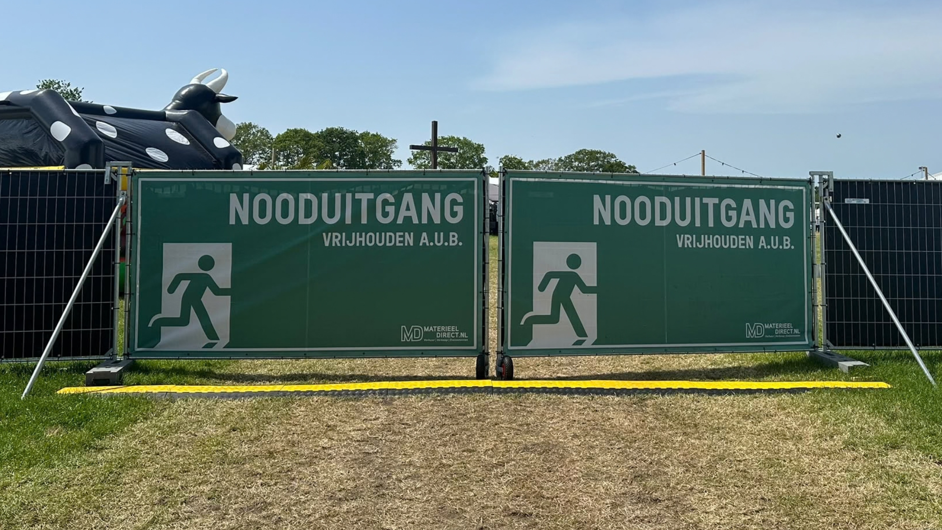 Nooduitgang in een bouwhek met scharnier, poortwiel en groen nooduitgang spandoek op een evenement
